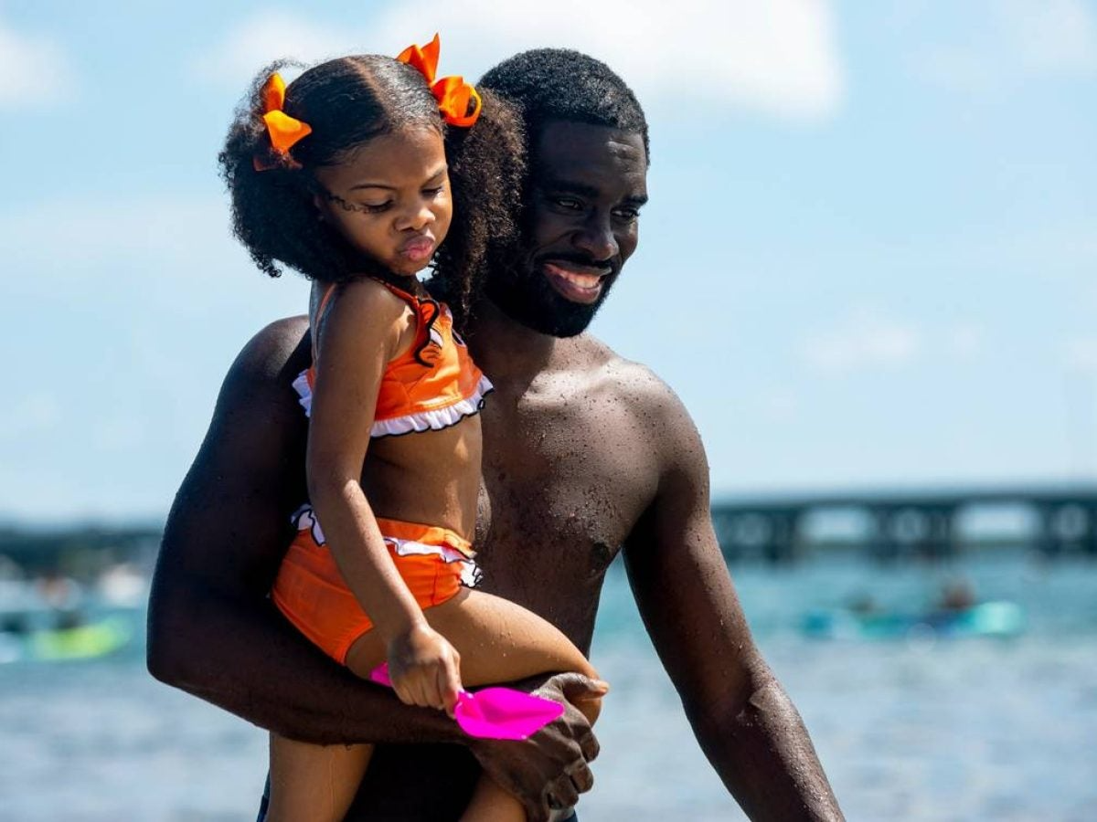Man carrying young girl at the beach.